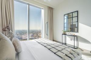 a bedroom with a white bed with a large window at GuestReady - Glamourous home in Downtown Dubai in Dubai