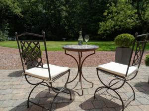 twee stoelen en een tafel met een wijnglas bij B&B Castel 't Haantje in Ruiselede