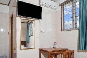 a room with a tv and a table and a mirror at Wisma Rumka in Jakarta