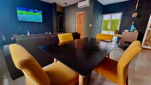 a dining room with a black table and yellow chairs at Playa Del Carmen Apartment in Playa del Carmen