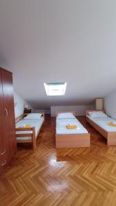 three beds in a room with wooden floors at Apartment SKY in Novalja