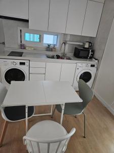 ソウルにあるHongdae ssuny houseの白いキャビネットとテーブルと椅子のあるキッチン
