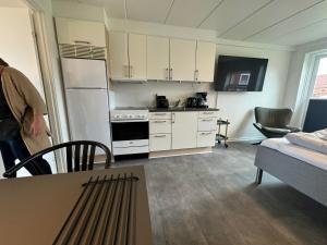 a kitchen with white cabinets and a table in a room at Hvide Sande Hotel in Hvide Sande