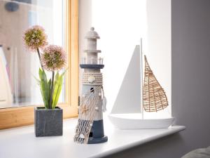 a shelf with a model of a lighthouse and a vase with flowers at Apartment Harbour Nights 4 by Interhome in Lossiemouth