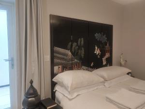 łóżko z białymi poduszkami i czarną deską w obiekcie Luxurious duplex design-flat Kensington w Londynie