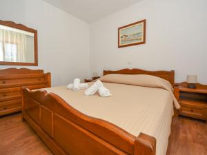 a bedroom with a large wooden bed with white sheets at Holiday Home Marko by Interhome in Sukošan