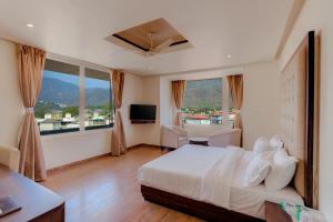 a hotel room with a bed and a large window at Hotel Vasundhara Palace in Rishīkesh