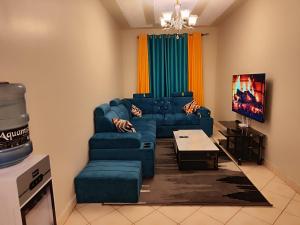 sala de estar con sofá azul y mesa en Romantic 1Bedroom Gateway in Kinoo, en Kikuyu
