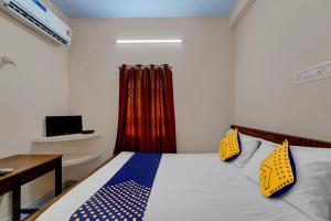 a bedroom with a bed with a desk and a television at SPOT ON RKH Inn in Chennai