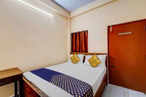 a small bedroom with a bed with yellow and blue pillows at SPOT ON RKH Inn in Chennai