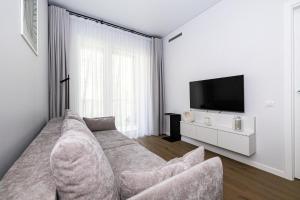 a living room with a couch and a tv at Coastal Haven Retreat, By Cohost in Palanga