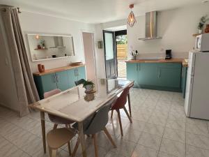 a kitchen with a table and chairs and a refrigerator at La P'tite maison de Trého in Tréhorenteuc +12 photos