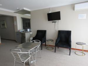 een kamer met stoelen en een tafel en een tv aan de muur bij St Helena Bay Hotel in St Helena Bay