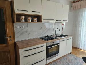 una cucina con mobili bianchi e un forno a piano cottura di Apartma Cipresa a Rogatec