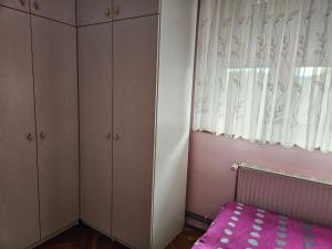 una camera da letto con un letto rosa e una finestra di Apartma Cipresa a Rogatec Altre 3 foto