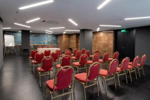 einen Konferenzraum mit roten Stühlen und einem Podium in der Unterkunft Astor Hotel in Athen