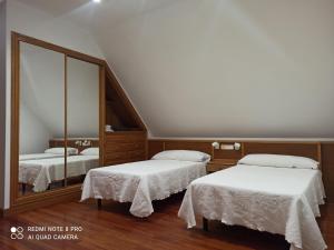 sypialnia z dwoma łóżkami i dużym lustrem w obiekcie Duplex en Sanxenxo con piscina y vistas al mar w mieście Sanxenxo +14 zdjęć