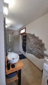 a bathroom with a sink and a stone wall at Il Rustico in Maccagno con Pino e Veddasca