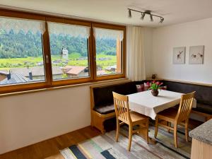 ein Esszimmer mit einem Tisch, Stühlen und einem Fenster in der Unterkunft Ferienwohnung Schoppernau in Schoppernau