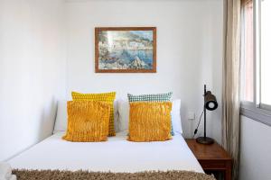 1 dormitorio con cama blanca y almohadas amarillas en 2 Bdr Apt In Cornella 5 Mins Form The Metro, en Cornellà de Llobregat