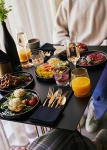 uma mesa com pratos de comida e copos de vinho em Amberton Green SPA Druskininkai em Druskininkai