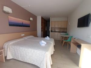 une chambre d'hôtel avec deux lits et une cuisine dans l'établissement Apartamentos Orvay, à Sant Antoni de Portmany