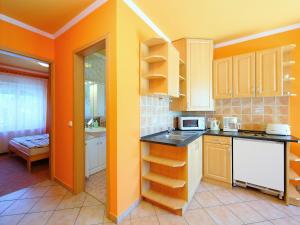 a kitchen with orange walls and white cabinets at Apartment Lakefront 1 by Interhome in Balatonlelle