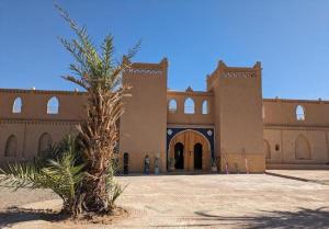 ein Gebäude mit einer Palme davor in der Unterkunft SANDSTAR PALACE in Merzouga