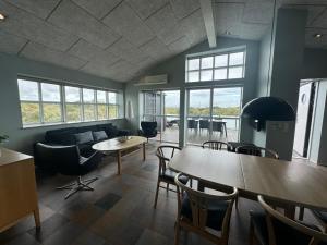 a living room with a couch and tables and chairs at Hvide Sande Hotel in Hvide Sande