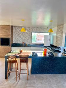 a kitchen with a counter with two chairs and a table at Central Praias III in Cabo Frio