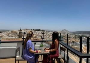 dwie kobiety siedzące przy stole na balkonie w obiekcie Apartamentos Antequera w mieście Antequera