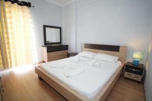um quarto com uma grande cama branca e uma televisão em “apHEARTment Gjirokastra” em Gjirokastër