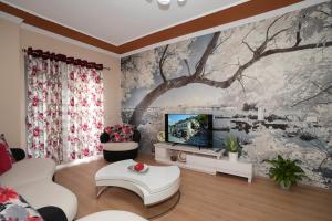 uma sala de estar com uma televisão e um mural de árvore em “apHEARTment Gjirokastra” em Gjirokastër
