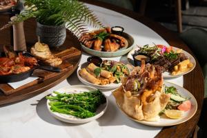 a table with many plates of food on it at Mill Hotel Milperra Panania in Panania