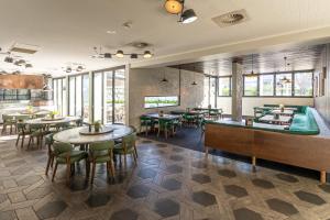 um restaurante com mesas, cadeiras e janelas em Mill Hotel Milperra Panania em Panania