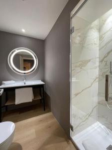 ein Bad mit einer Dusche, einem Waschbecken und einem Spiegel in der Unterkunft AC Hotel by Marriott Clodio Roma in Rom