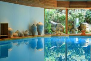 - une grande piscine avec vases dans une chambre dans l'établissement Grand Hôtel De Cala Rossa & Spa Nucca, à Porto-Vecchio