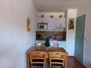 una pequeña cocina con mesa de madera y sillas en Charmant 2 Pièces pour 4 Personnes avec Balcon et Accès Piscine à Superdevoluy - FR-1-504-549, en Le Dévoluy