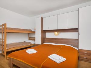 a bedroom with a large orange bed with two bunk beds at Apartment Cico-2 by Interhome in Gdinj