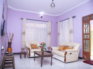 a living room with purple walls and white furniture at Aminata Bed & Breakfast in Moshi