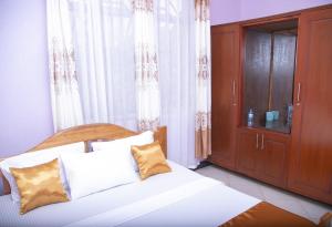 a bedroom with a bed and a wooden cabinet at Aminata Bed & Breakfast in Moshi
