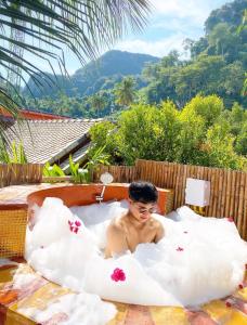 Phi Phi Maiyada Resort- SHA Certified في جزيرة في في: رجل يستلقي في حوض الاستحمام مع الغيوم