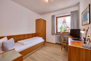 Habitación con cama y escritorio con ordenador. en Hotel Antonia, en Oberammergau