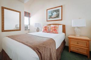 a bedroom with a bed and a table with a lamp at Banyan Harbor Resort in Lihue