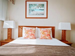 Banyan Harbor Resort في ليهو: غرفة نوم بسرير ومخدات ومصباحين