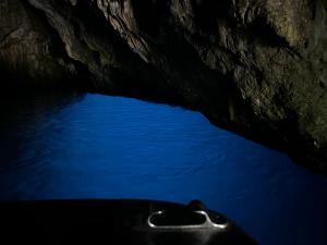 ein Boot in einer dunklen Höhle mit blauem Wasser in der Unterkunft Villa delle Muse da Imma in Palinuro
