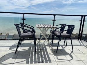 2 stoelen en een tafel op een balkon met uitzicht op de oceaan bij Seascape - 2 bedroom flat with panoramic sea views in Hollington
