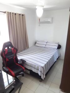 a bedroom with a bed and a red chair at Ótimo apartamento, bem localizado in Aracaju