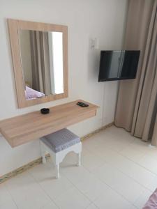 a bathroom with a mirror and a table with a stool at Hotel Mezri in Monastir