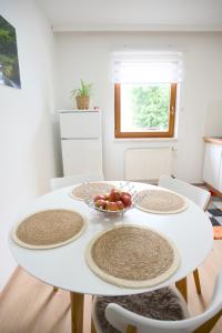 a white dining room table with plates and a bowl of fruit at Aparment L&G in Spielberg +7 photos